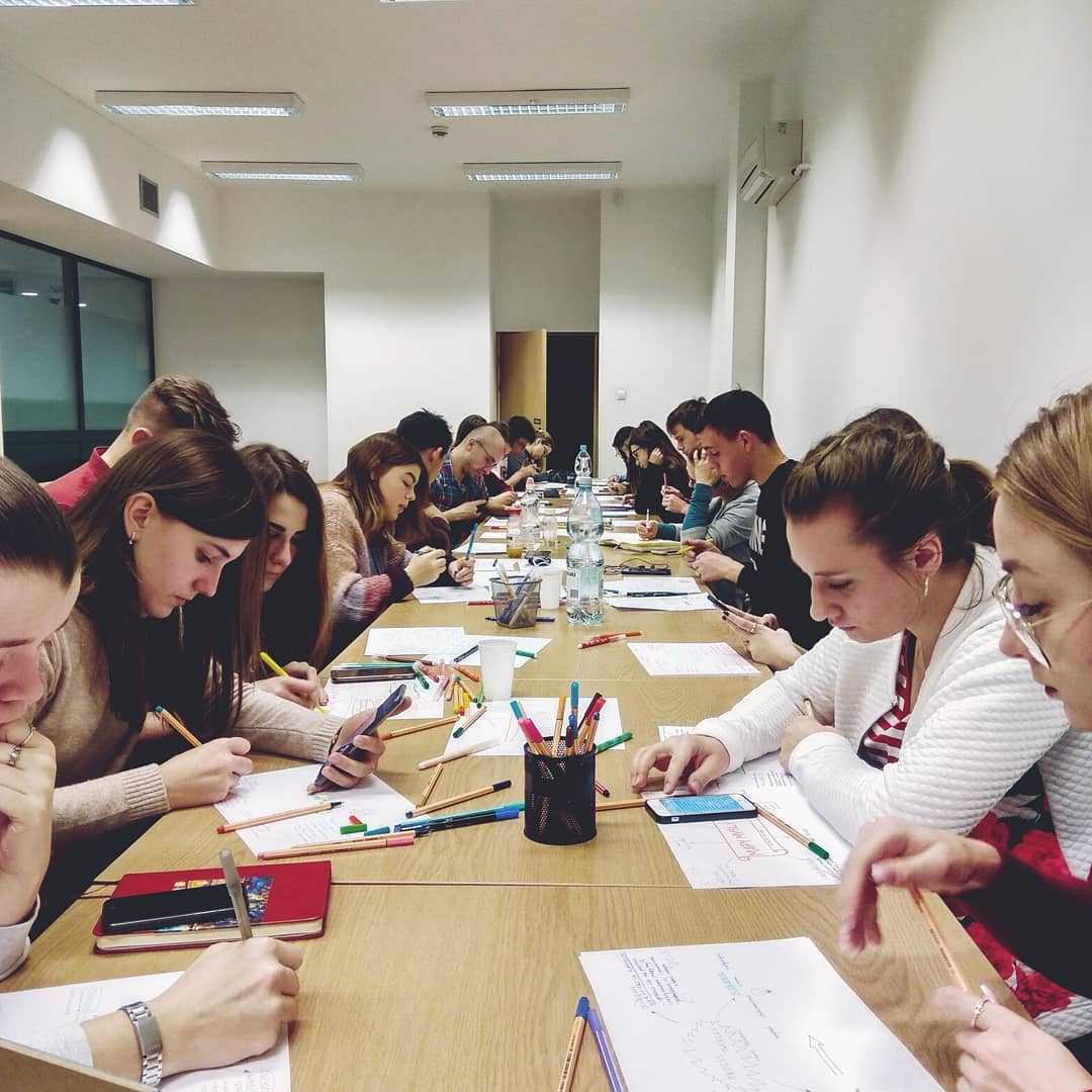 zdjęcie uczestników warsztatów notowania wizualnego tworzących notatki przy stole